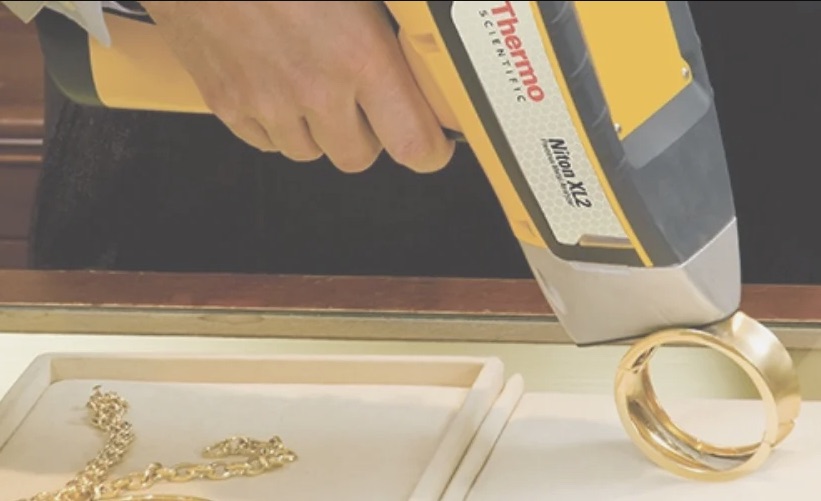 Handheld XRF analyzer testing a gold ring on the counter